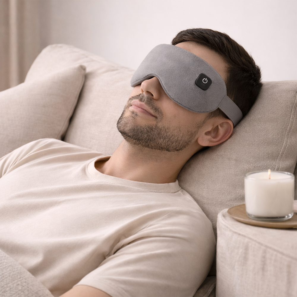 Man wearing beprana heated eye mask for nervous system regulation while resting on a sofa