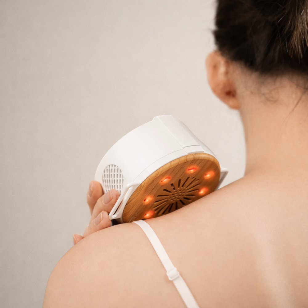 Woman using beprana portable heat therapy device on shoulder