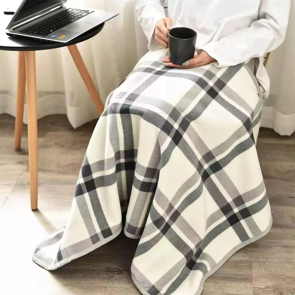 Grey plaid wearable blanket draped over legs while working from home with laptop.