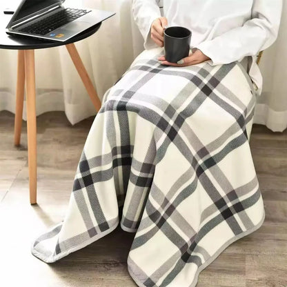 Grey plaid wearable blanket draped over legs while working from home with laptop.